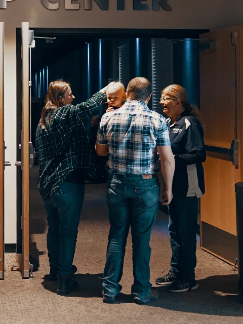 Sagebrush volunteers welcoming a family at an auditorium entrance.